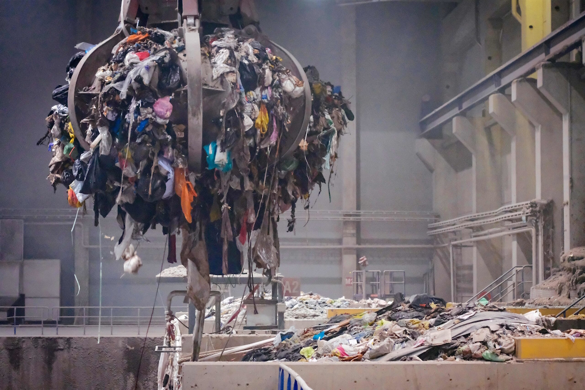 waste management gripper holds garbage ready to deploy on roller convey