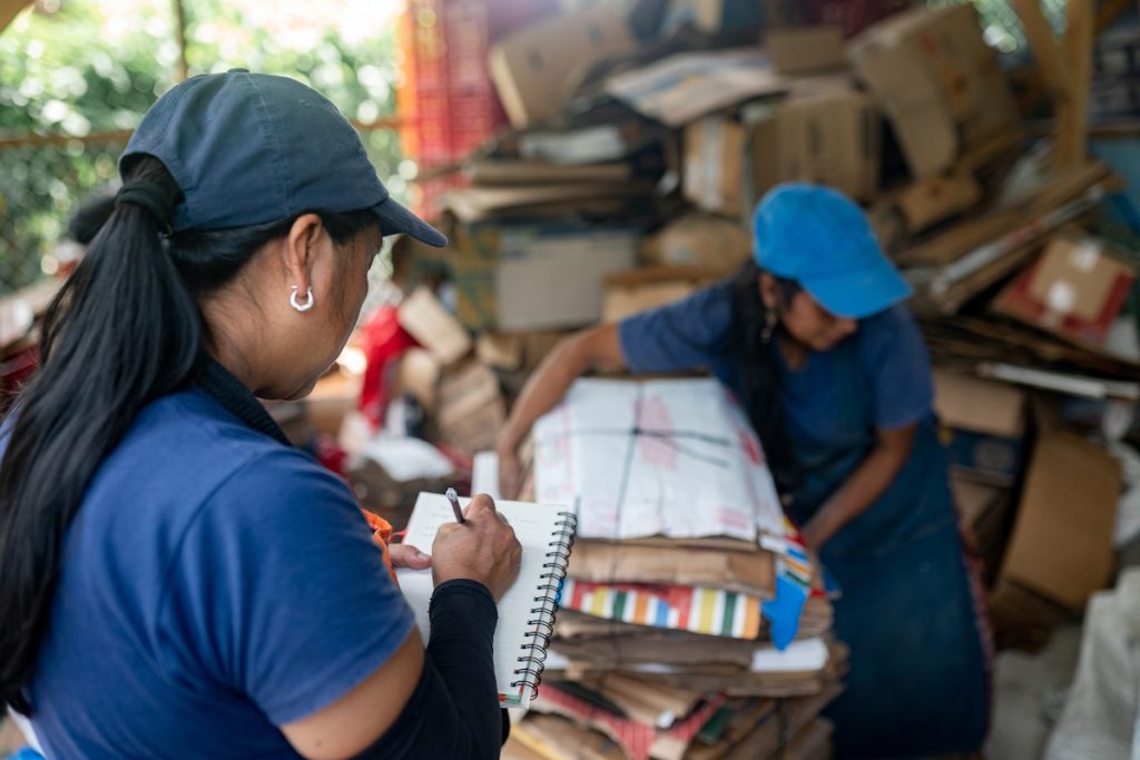 business revenue woman noting recycled cardboard inventory